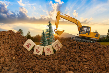 Concept Happy new year 2023,With Crawler excavator lift up bucket in construction site .On sunbeam...