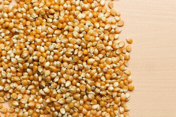 Pile of yellow corn seeds isolated on brown wooden background, for popcorn.