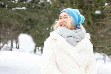 Portrait of happy beautiful blonde woman with snow in winter nature.