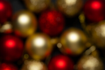 Christmas balls of red and gold color in blur on a black background. Christmas background without focus, screensaver.