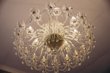 Luxury expensive chandelier hanging from the ceiling in the apartment. Crystal chandelier in the room. Close-up