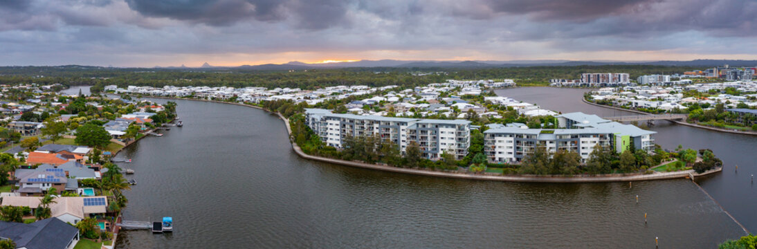 Aerial panorama view of real estates and apartment buildings lining a canal under a dull sunset sky