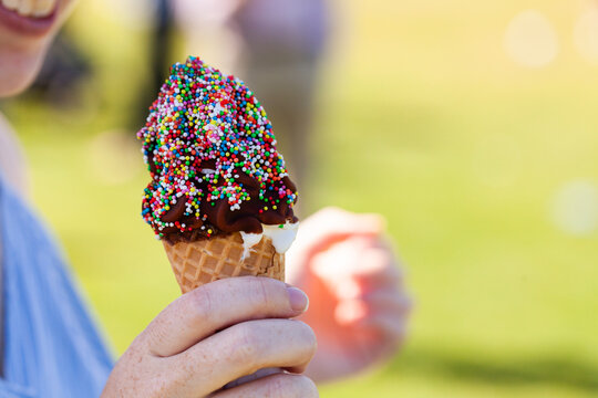 person holding ice cream with waffle cone and sprinkles