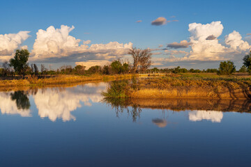 Storm clouds reflected in the water of an irrigation channel