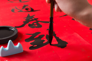 writing spring festival couplets to celebrate Chinese new year holidays.(the write word meaning...