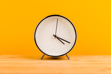 Alarm clock on yellow background, time concept
