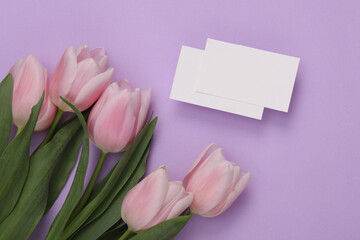 bouquet of tulips with business cards on lavender color background. Top view