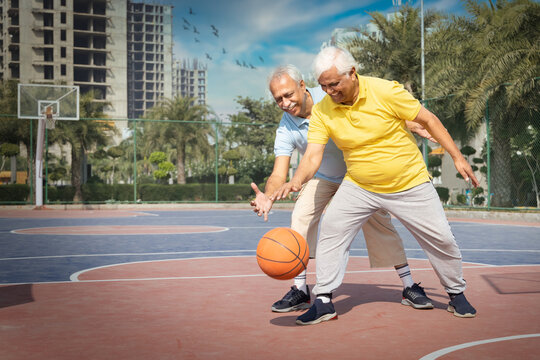 Two Seniors On The Basketball Field Playing Basket.