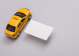 White Blank business card and toy taxi car on gray background. Creative Mockup for presentations and corporate identity.