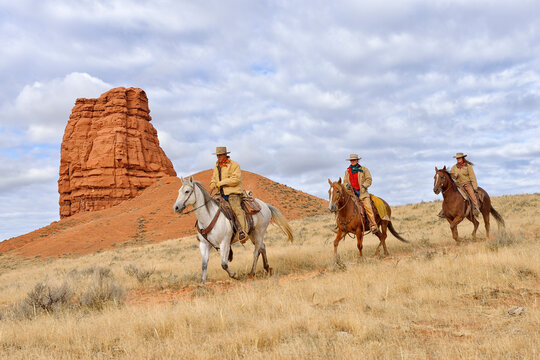 Cowboy and Cowgirls Riding Horses with Castel Rock in the background, Shell, Wyoming, USA