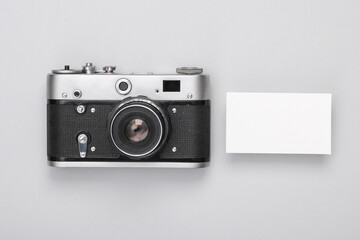 Retro camera with a business card on a gray background. Photographer branding