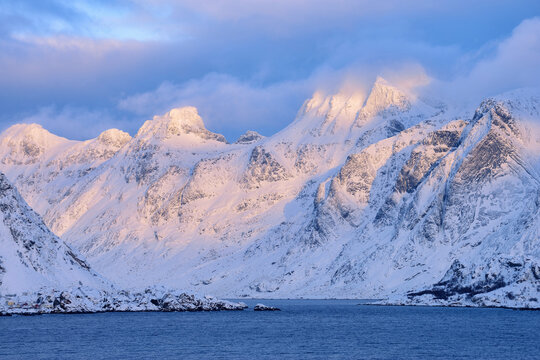 View from the Spellmannsbukta to Kunna Island and Flakstadoya. Mountains covered with snow in winter, sunset. Kunna Island, Flakstadoy, Lofoten, Norway, Scandinavia.
