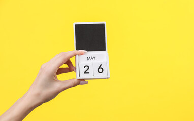 Block calendar with date may 26 in female hand on yellow background