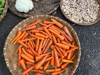 fresh, organic and imperfect carrots on round bamboo tray being sold at traditional market
