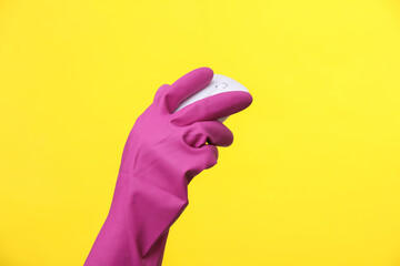 Hand in purple rubber cleaning glove holding pc mouse on a yellow background.