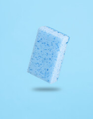 Sponge levitating on blue background with a shadow. Cleaning concept