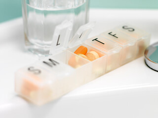 Pills in Dispenser with Glass of Water