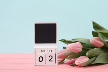 Block wooden calendar with the date March 02 and tulips on a pastel background. Spring composition