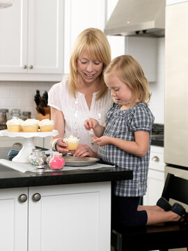 Mother and Daughter Decorating Cupcakes in open concept Kitchen, Toronto, Ontario, Canada