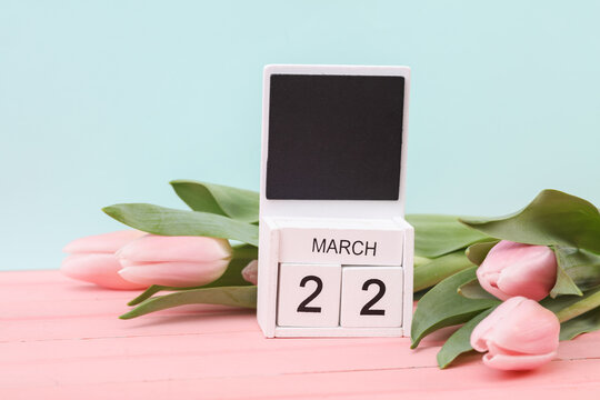 Block wooden calendar with the date March 22 and tulips on a pastel background. Spring composition