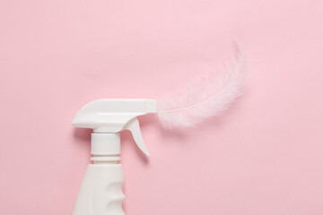 Detergent spray bottle with feather on pink background. Creative layout. Cleaning concept