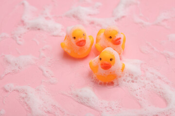 Rubber ducklings with foam on a pink background