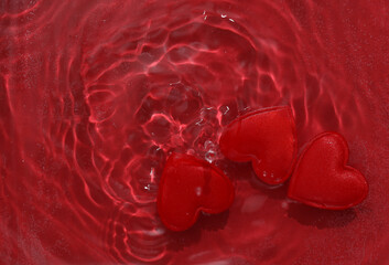 Red hearts in red water with shadows. Top view