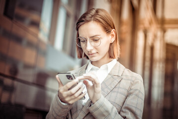 Young modern business woman using smartphone on the background of business building