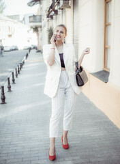 Charming smiling fashion woman talking on the phone on a european street