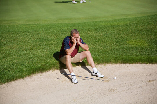 Man Sitting by Sand Trap on Golf Course