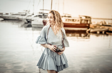 Portrait of a cute female tourist with a camera on the background of the yacht club