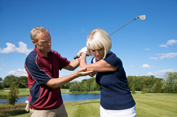 Man Helping Woman With Her Golf Swing