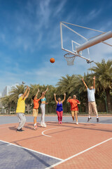 Family playing basketball together at basketball court.