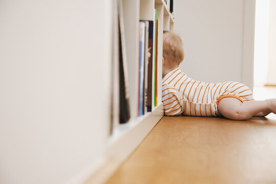 Baby Lying on Floor Looking in Bookshelf