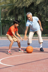 Fototapeta premium Grandfather and his grandson enjoying and playing together on basketball court.