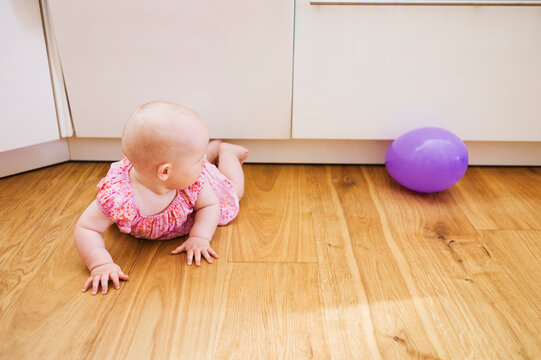 Baby Girl lying on floor and Looking at Purple Balloon