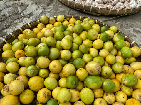 various vegetables tomatoes, chilli, red onion, corn, carrot, lime, garlic being sold at asian traditional market. colorful vegetables on round bamboo tray at traditional market floor