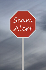 red road sign with text of Scam Alert and dark sky