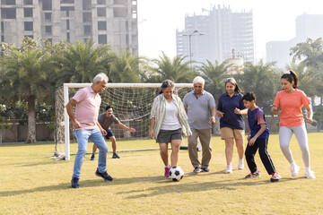 Happy multi generation family playing football together in the football ground.