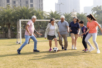 Happy multi generation family playing football together in the football ground.