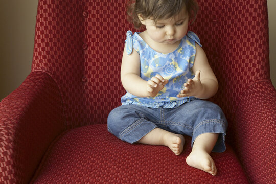 Little Girl Sitting on Red Chair