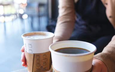 Closeup of a woman holding and serving two cup of hot coffee in cafe