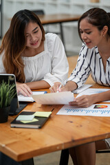 Fototapeta premium Shot of two businesswoman working together. Creative female executives meeting in an office working on document and smiling.