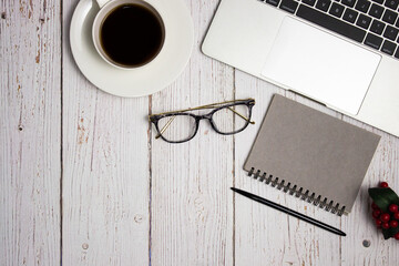 Working items in grey theme with coffee, glasses, notebook and computer over the wooden table.