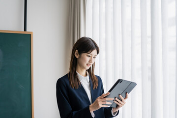 タブレットPCを見るスーツ姿の日本人女性