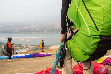 Paraglider on the ground. paragliders with full flight equipment look on soaring another...