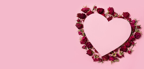 Heart with dry rose flowers on a pink background. Flowers in the shape of a heart. Postcard for March 8, St. Valentine's Day, Women's Day. Banner. Mockup. Copy space.