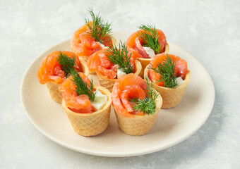 Snack with red fish on a plate on a light background. View from above. Copy space.
