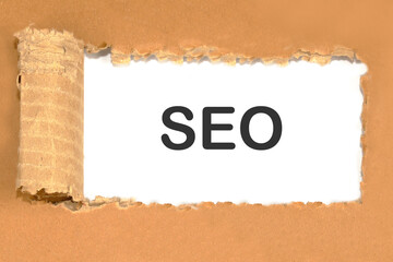 Text SEO on white paper under a torn piece of cardboard