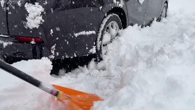 車の周囲を雪寄せしている　駐車場　冬　大雪　スコップ